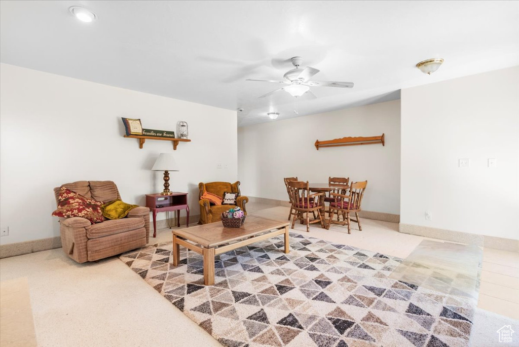 Carpeted living room with ceiling fan and baseboards