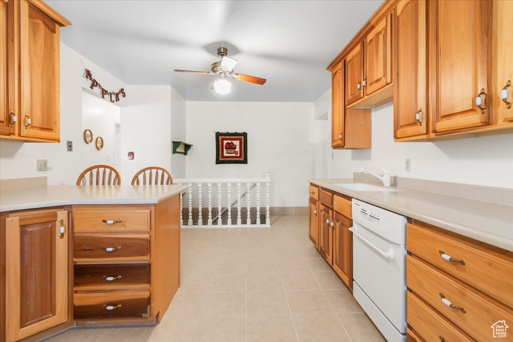 Kitchen featuring a sink, white dishwasher, ceiling fan, light countertops, and brown cabinets