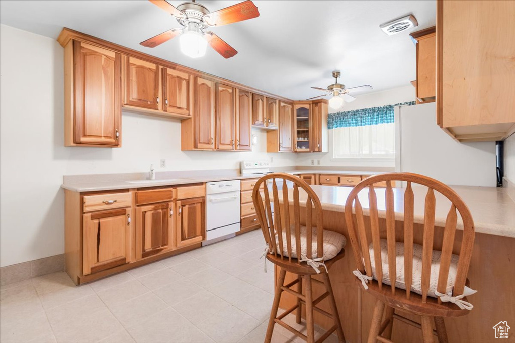 Kitchen featuring white dishwasher, a ceiling fan, a sink, light countertops, and glass insert cabinets