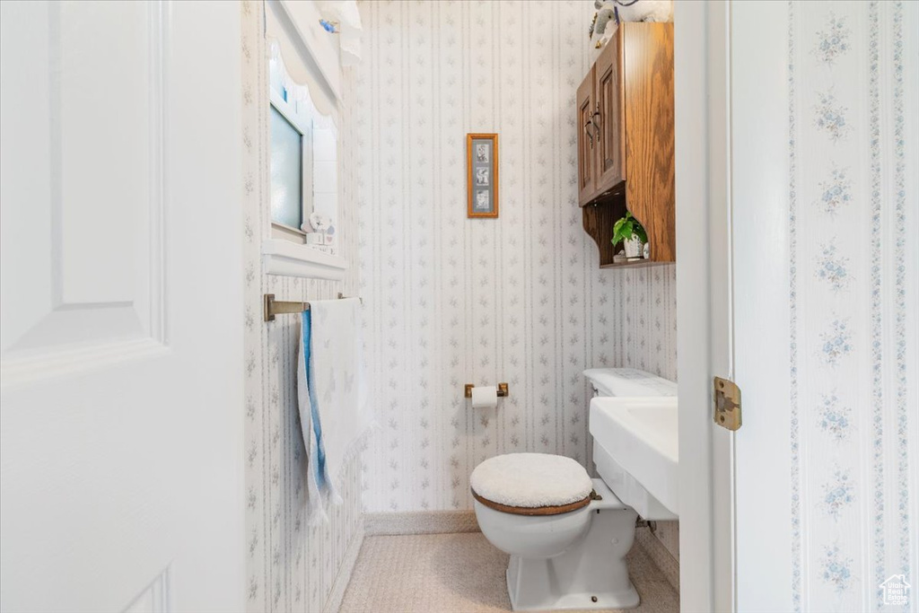 Half bath featuring toilet and wallpapered walls