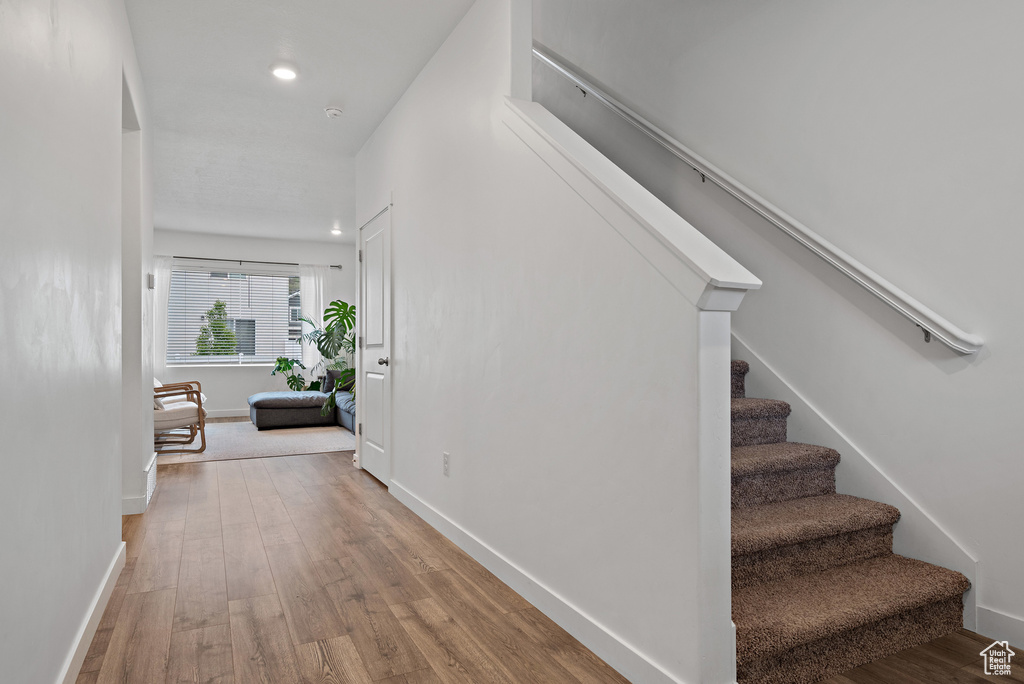 Stairway with wood finished floors, baseboards, and recessed lighting