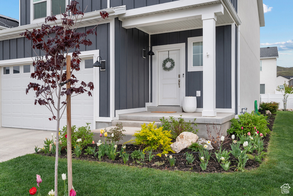 Doorway to property featuring board and batten siding, driveway, and a yard