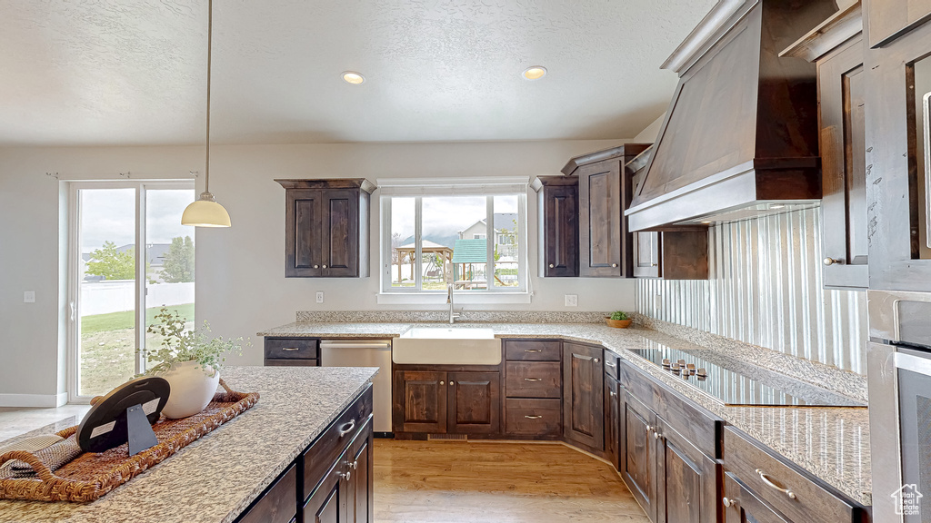 Kitchen with custom exhaust hood, a sink, dishwasher, a textured ceiling, and black electric stovetop