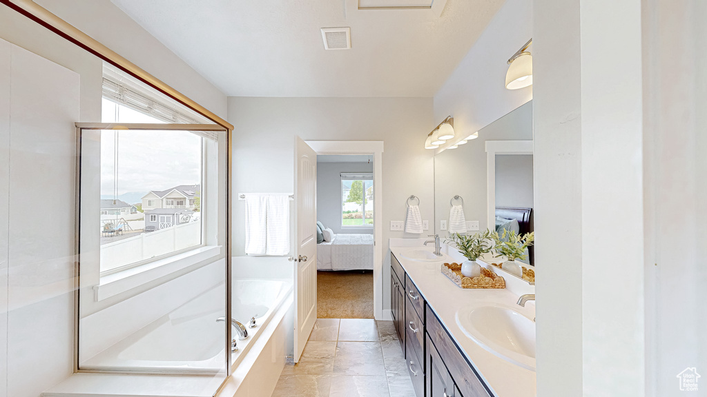 Ensuite bathroom featuring double vanity and a bath