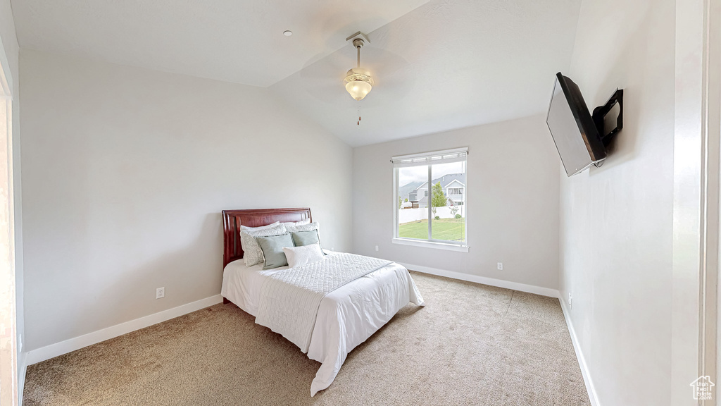 Bedroom with light carpet, vaulted ceiling, and baseboards