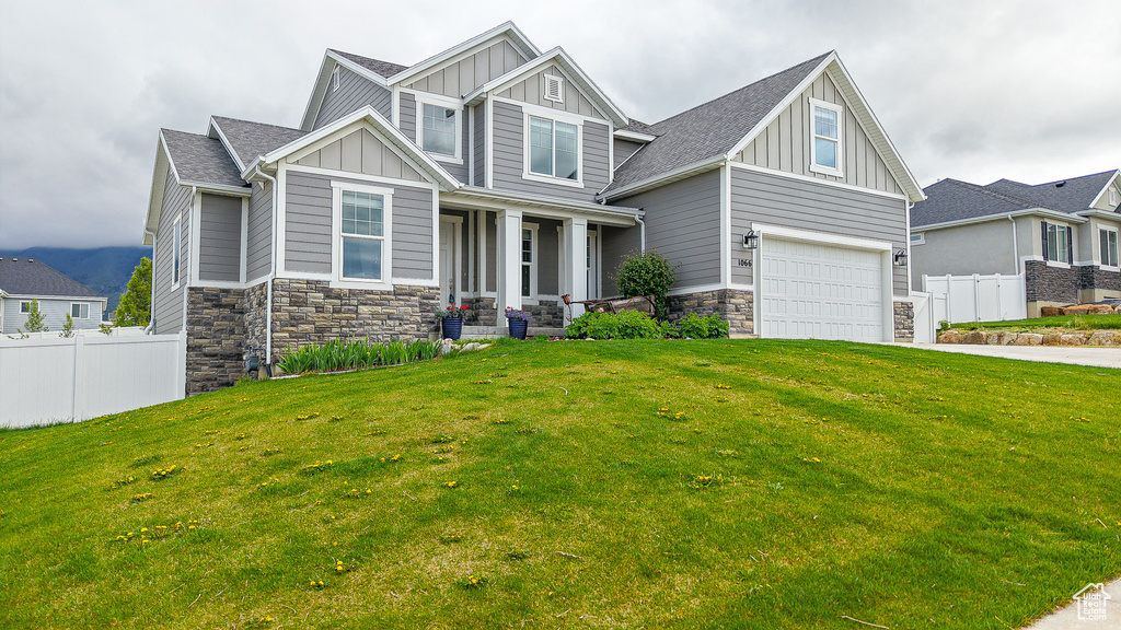 Craftsman-style house with board and batten siding, covered porch, stone siding, concrete driveway, and a garage
