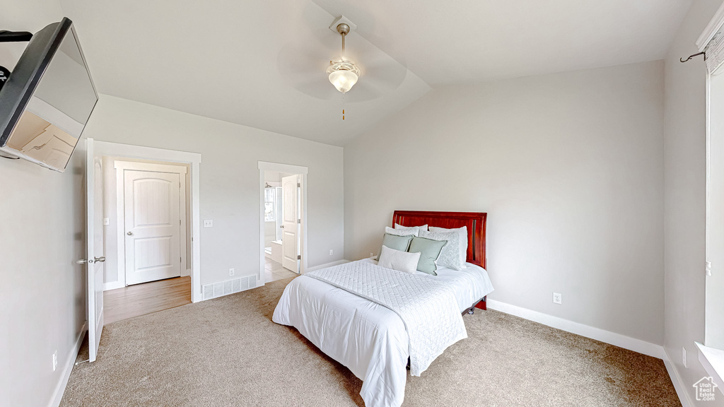 Carpeted bedroom with lofted ceiling, baseboards, ensuite bathroom, and ceiling fan