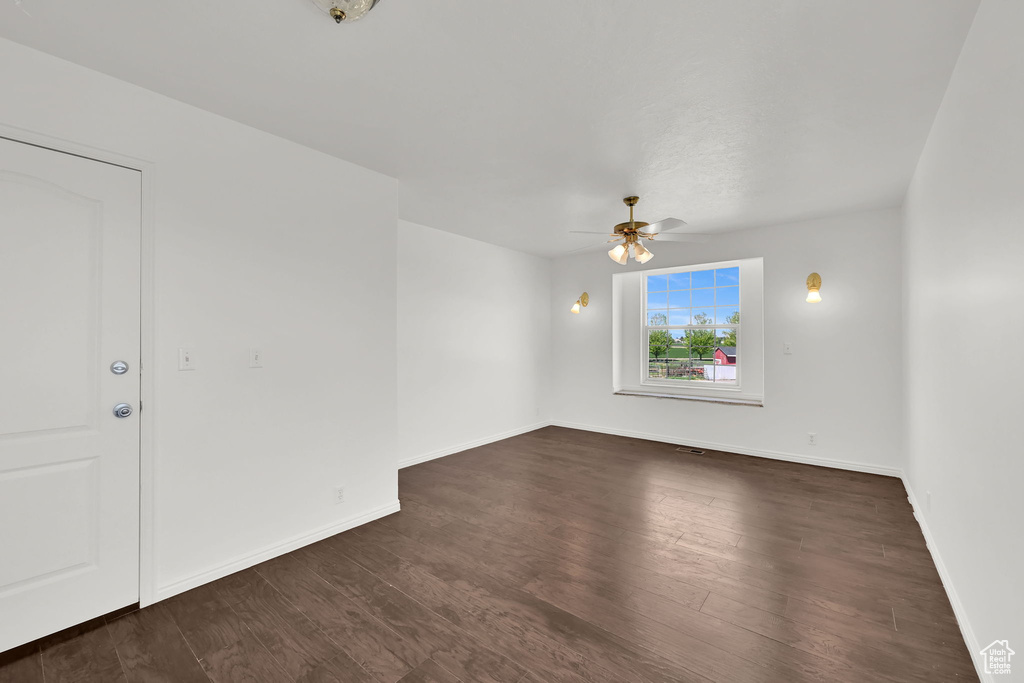 Spare room featuring a ceiling fan, dark wood-type flooring, and baseboards