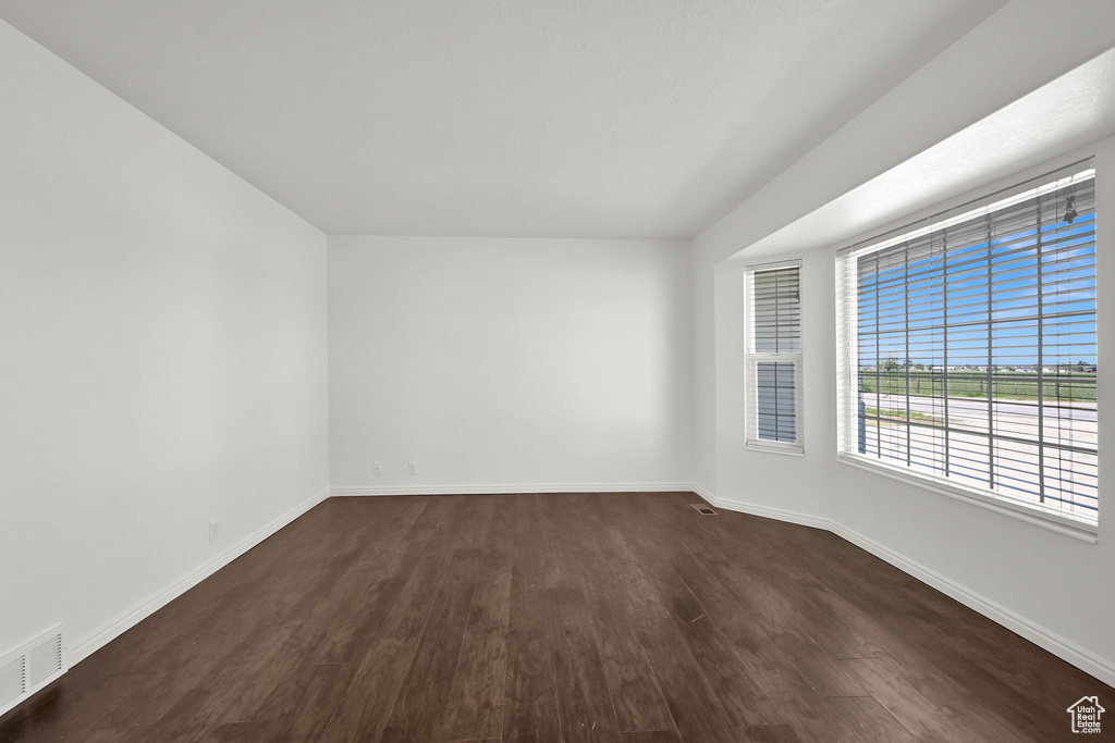 Unfurnished room featuring dark wood finished floors and baseboards