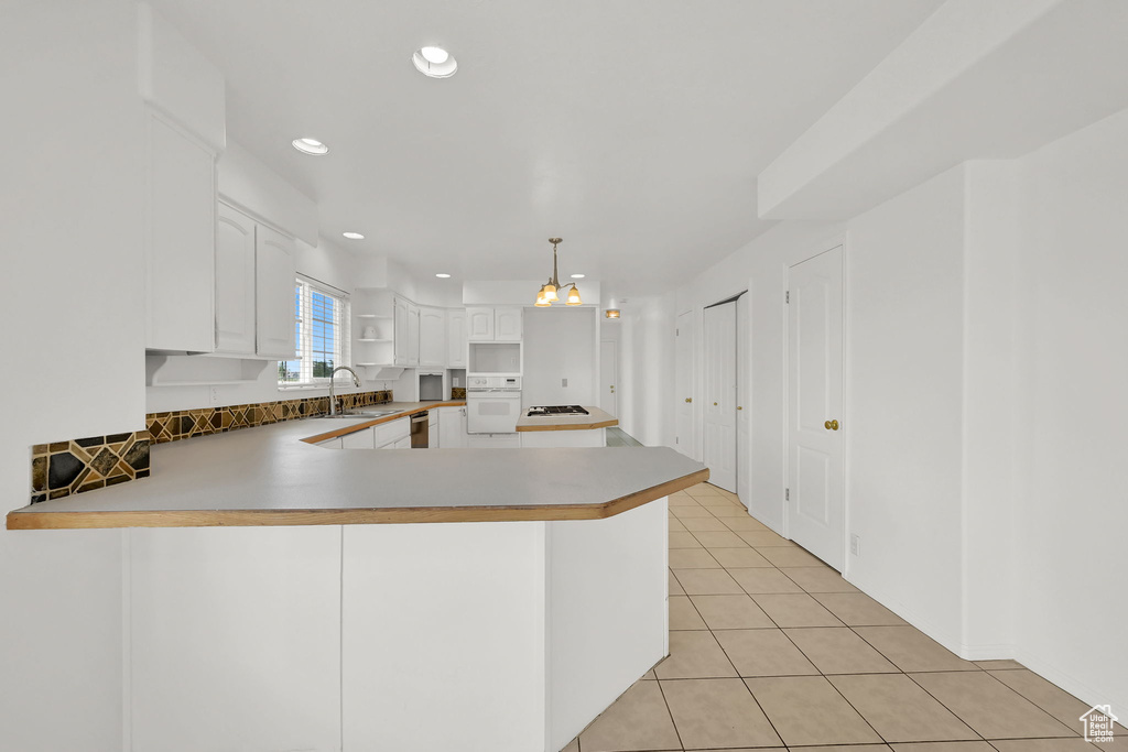 Kitchen featuring white oven, a peninsula, a sink, stainless steel dishwasher, and gas stovetop