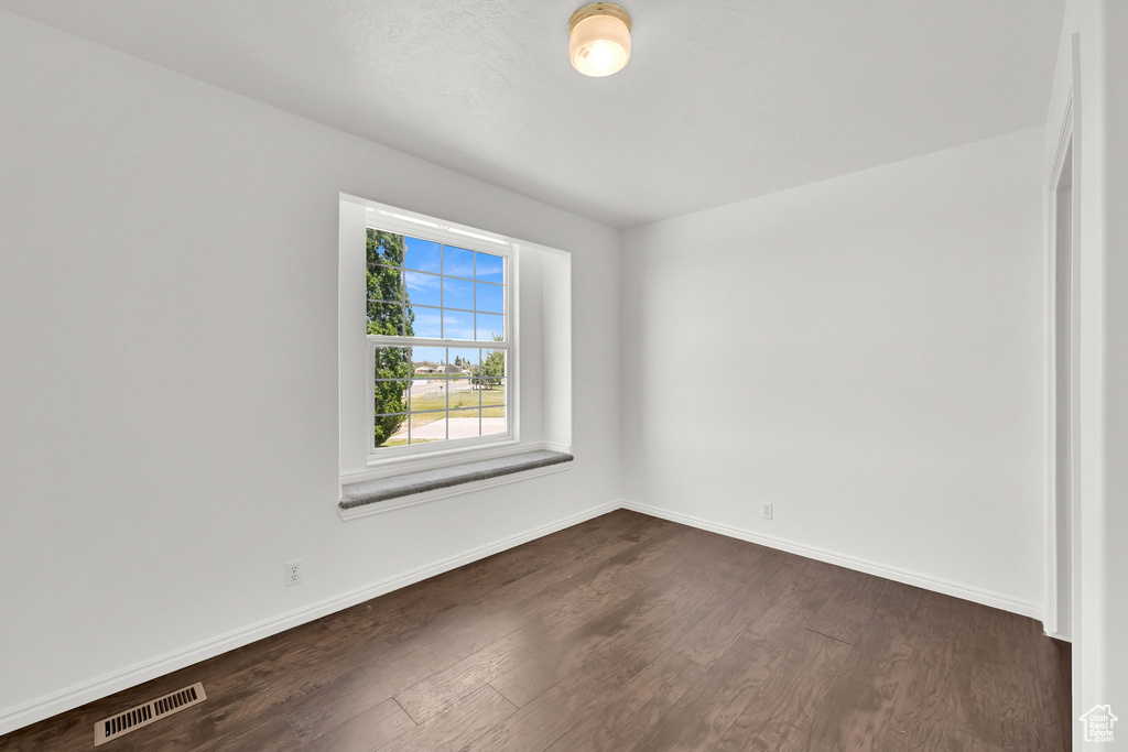 Unfurnished room with dark wood finished floors and baseboards