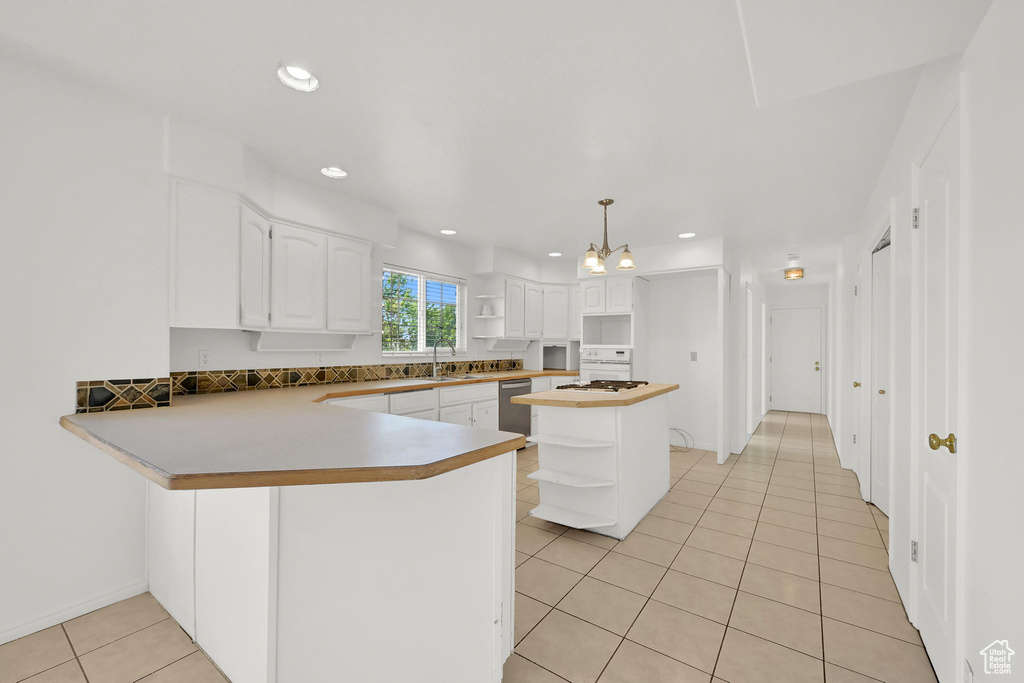 Kitchen with open shelves, light tile patterned floors, dishwasher, white cabinets, and a peninsula
