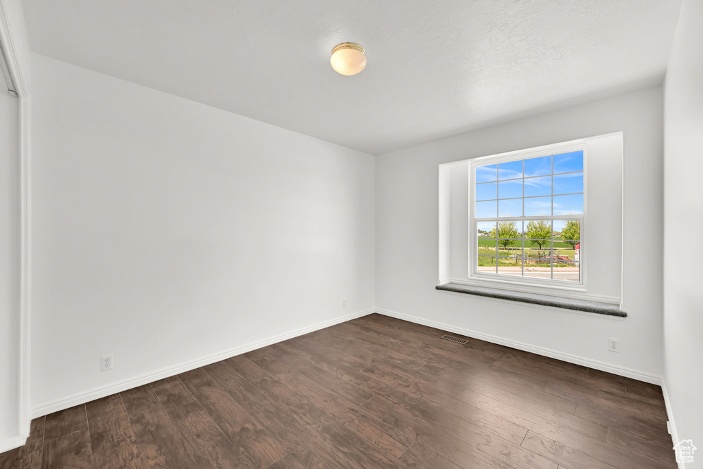 Unfurnished room featuring dark wood-type flooring and baseboards