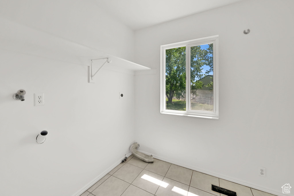 Laundry room with electric dryer hookup, baseboards, and light tile patterned floors