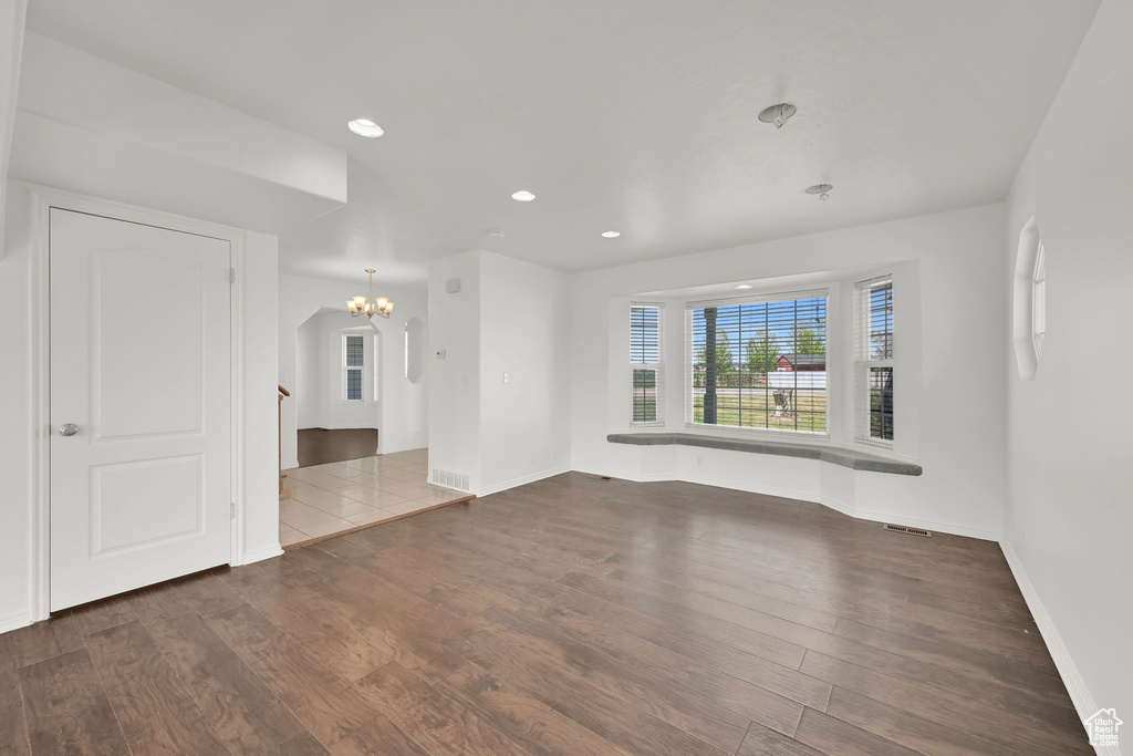 Empty room with a chandelier, baseboards, wood finished floors, and recessed lighting