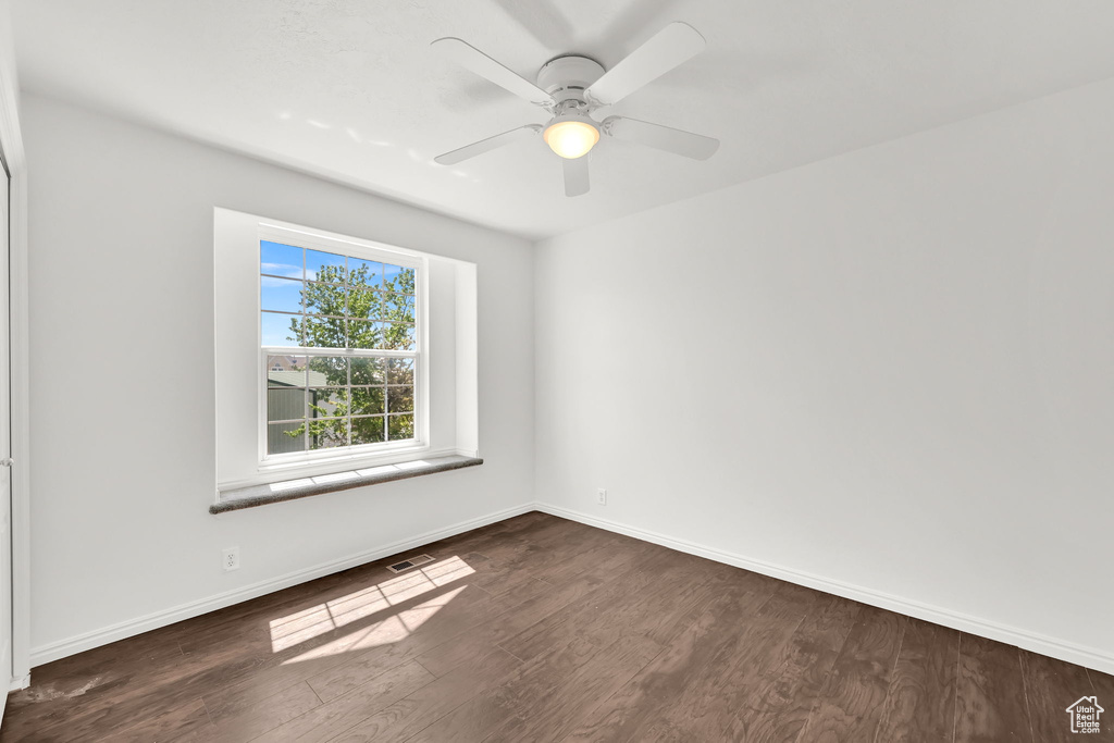 Spare room featuring dark wood-style floors, baseboards, and a ceiling fan