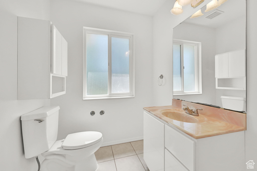 Half bath with tile patterned floors, toilet, vanity, and baseboards