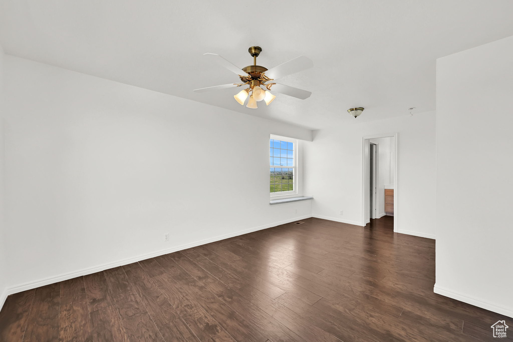 Unfurnished room with dark wood-style flooring, ceiling fan, and baseboards