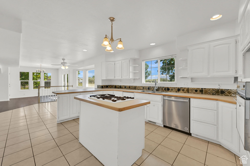 Kitchen featuring stainless steel dishwasher, white gas cooktop, a chandelier, a sink, and open shelves