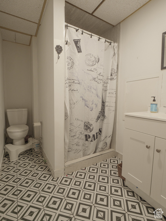 Bathroom with a paneled ceiling, toilet, curtained shower, tile patterned floors, and baseboards