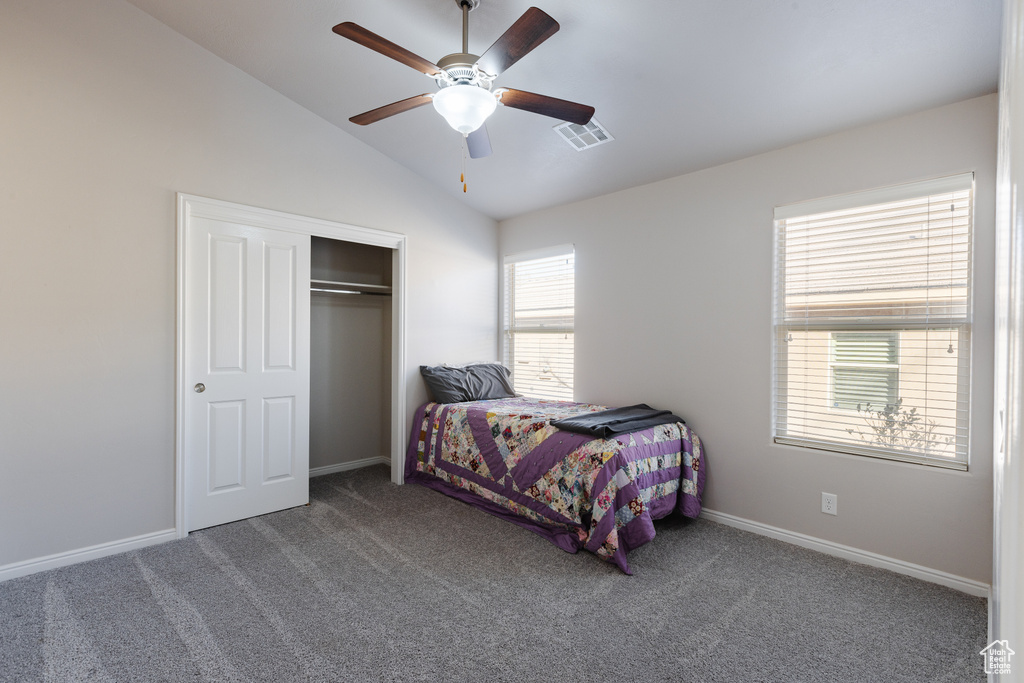Bedroom with a closet, visible vents, carpet, baseboards, and lofted ceiling