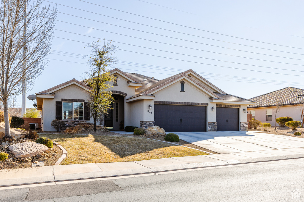 View of front of home featuring driveway, a tiled roof, stucco siding, a front lawn, and a garage