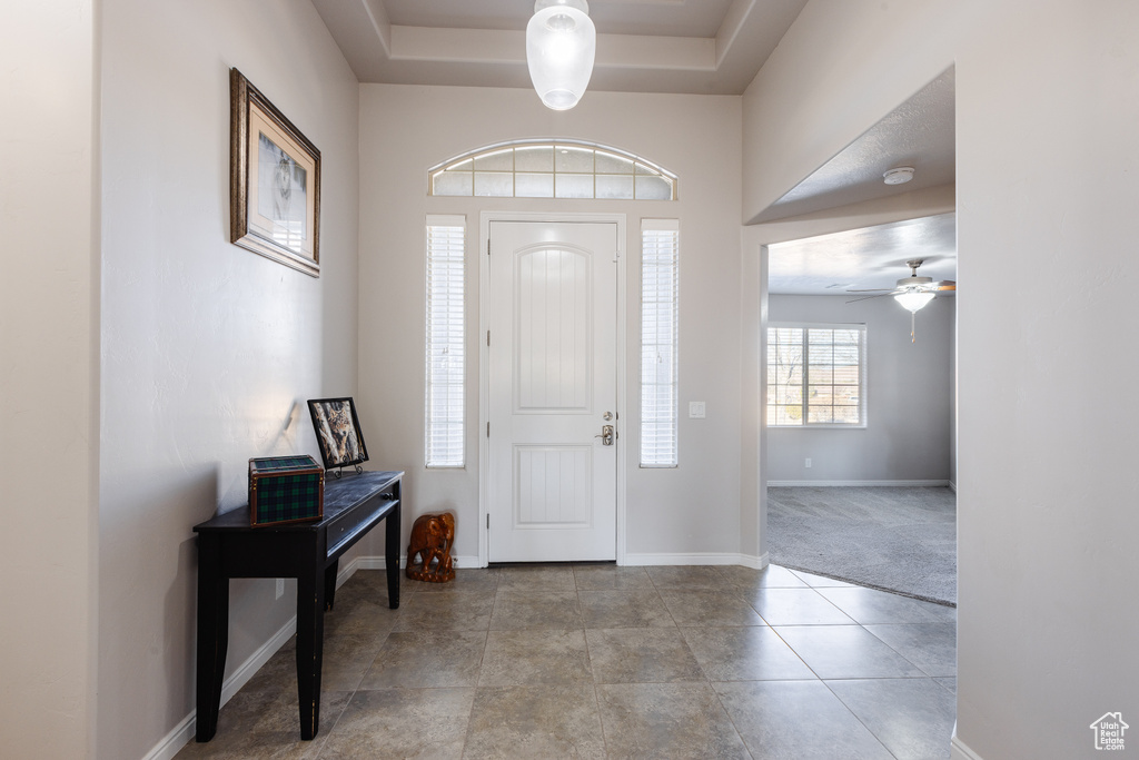 Foyer featuring baseboards, a raised ceiling, ceiling fan, and tile patterned floors