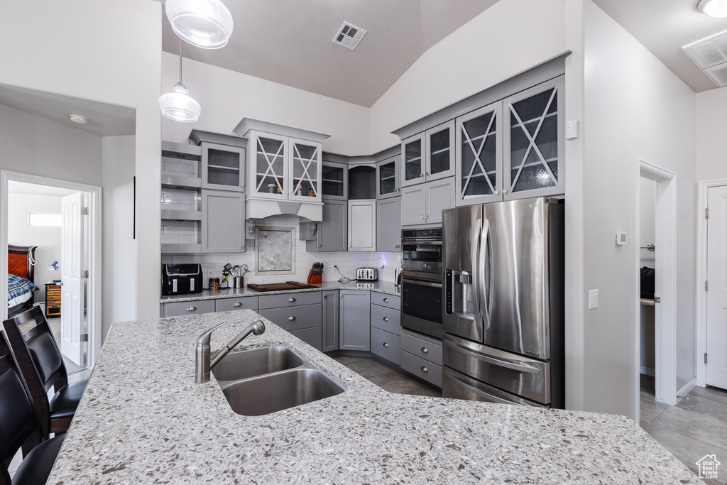 Kitchen with a sink, decorative backsplash, gray cabinets, visible vents, and appliances with stainless steel finishes