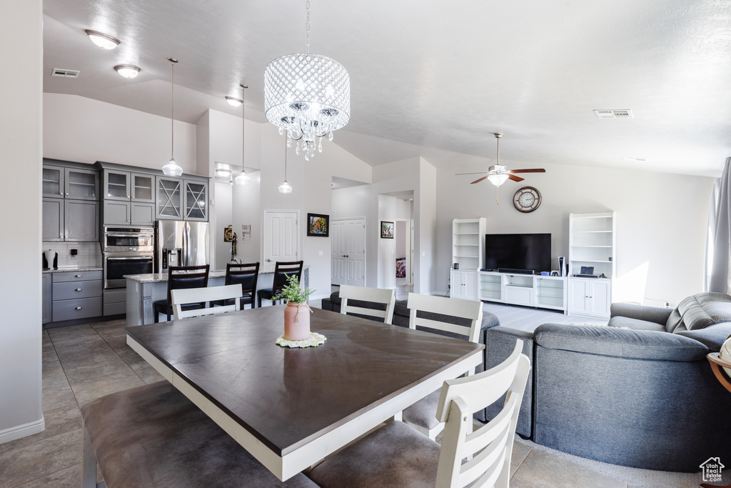 Dining area featuring visible vents, ceiling fan with notable chandelier, and high vaulted ceiling