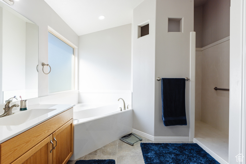Bathroom with tile patterned floors, vanity, and a bath