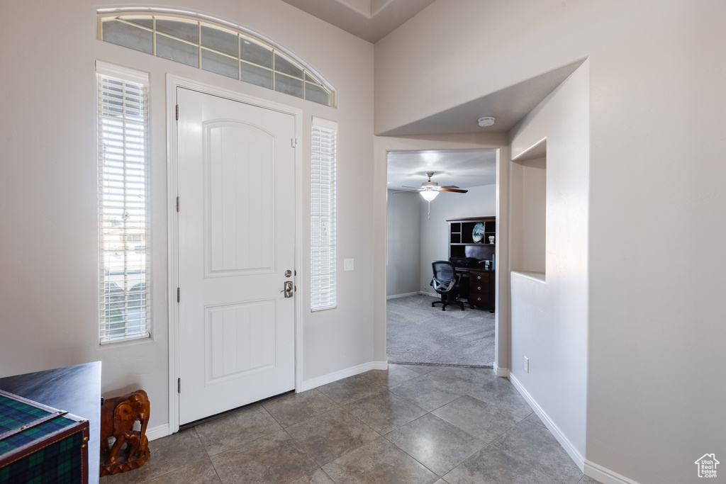 Foyer entrance with a ceiling fan and baseboards