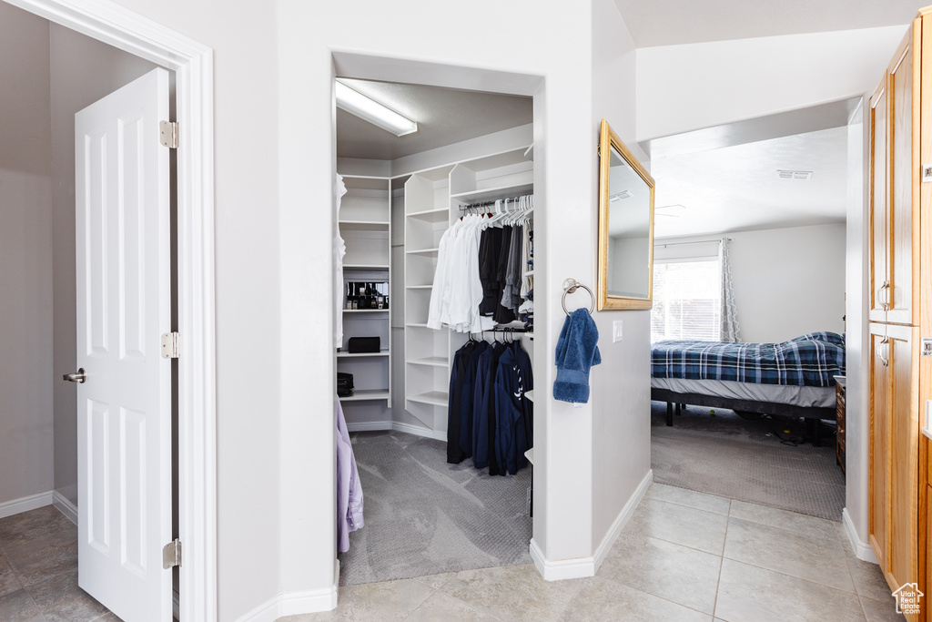 Walk in closet with light tile patterned floors, visible vents, and light colored carpet