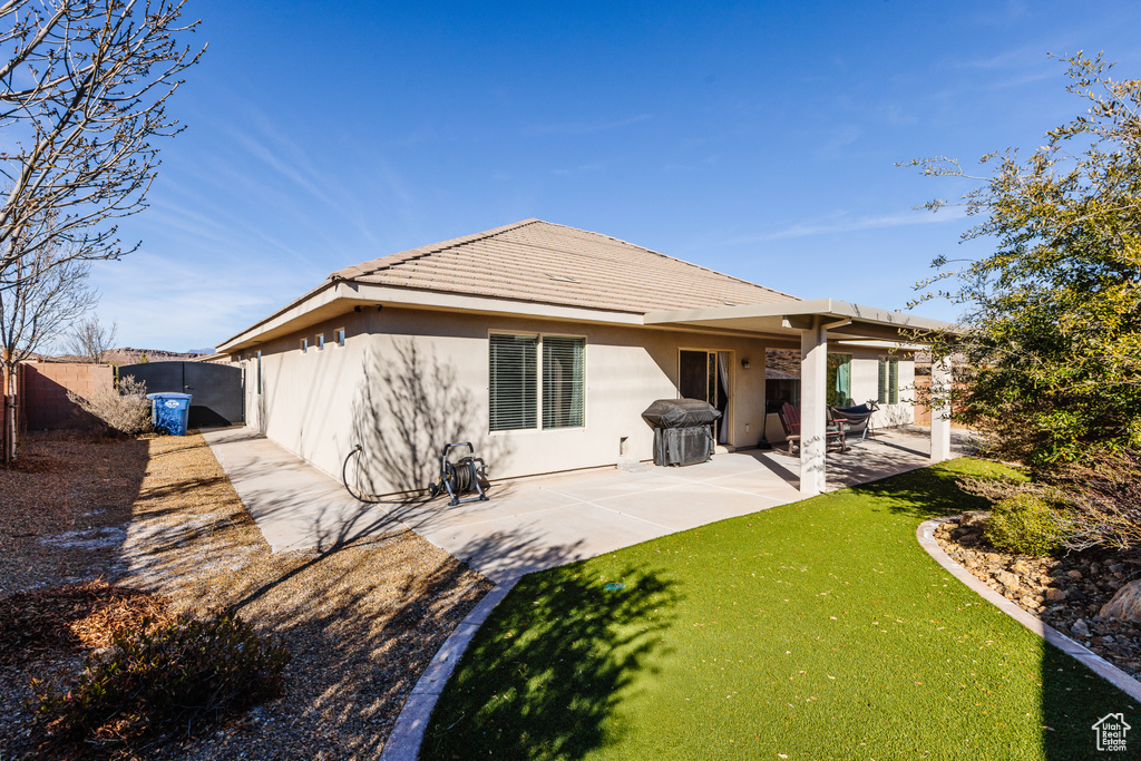 Back of house with a fenced backyard, stucco siding, a tile roof, a patio area, and a lawn