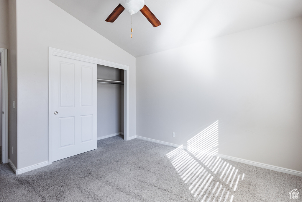 Unfurnished bedroom featuring carpet, vaulted ceiling, and a closet