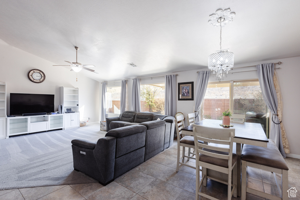 Living area with a healthy amount of sunlight, visible vents, vaulted ceiling, and ceiling fan with notable chandelier