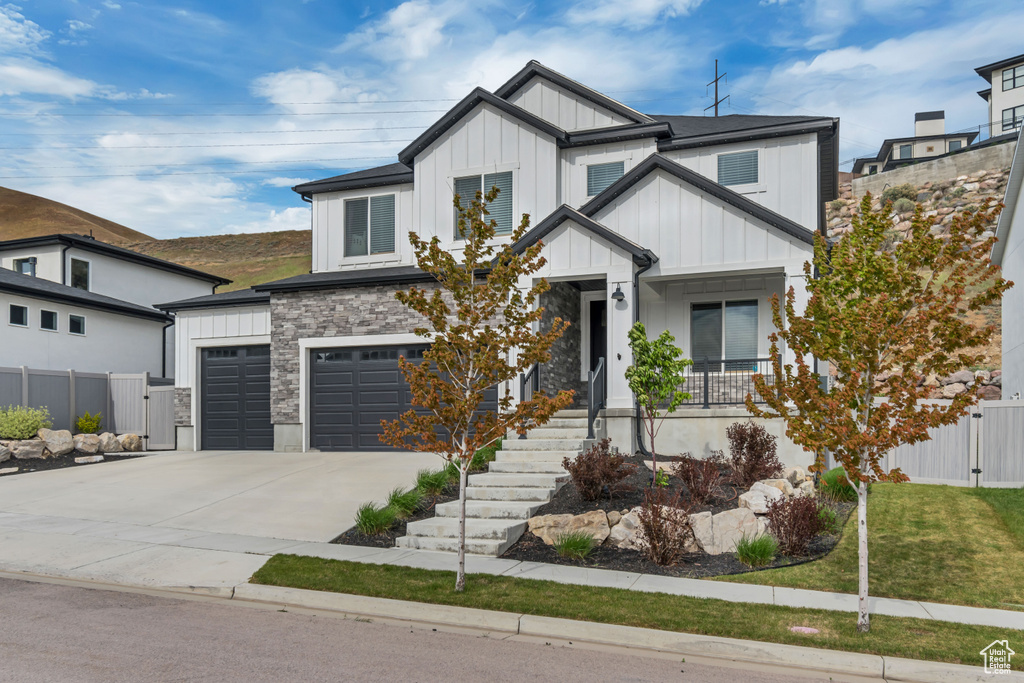 View of front of home featuring board and batten siding, fence, driveway, a garage, and a porch