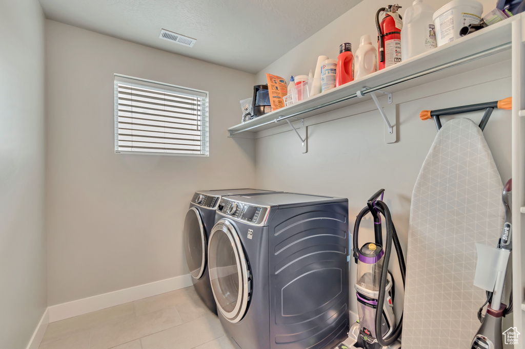 Laundry area featuring washing machine and clothes dryer, baseboards, and light tile patterned floors