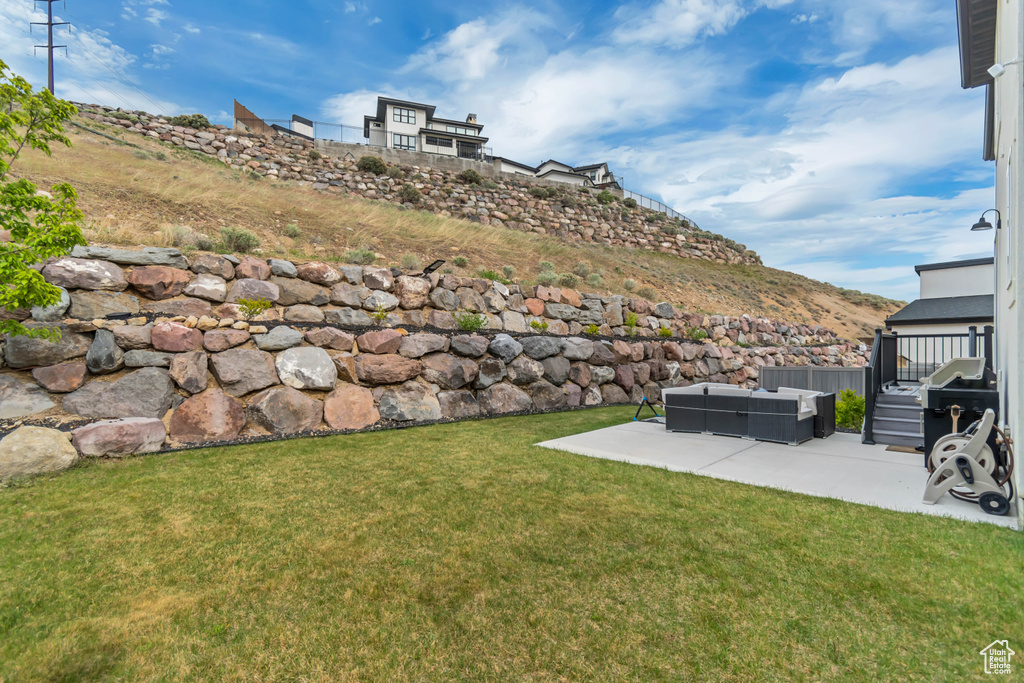 View of grassy yard featuring a patio area, an outdoor living space, and a mountain view