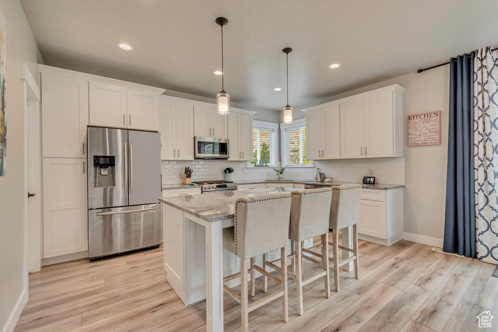Kitchen featuring appliances with stainless steel finishes, light wood-style floors, decorative backsplash, a center island, and recessed lighting