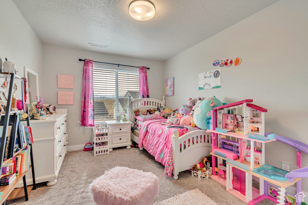 Bedroom featuring a textured ceiling, light colored carpet, and baseboards