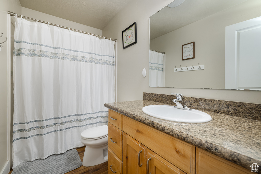 Full bath featuring wood finished floors, toilet, and vanity