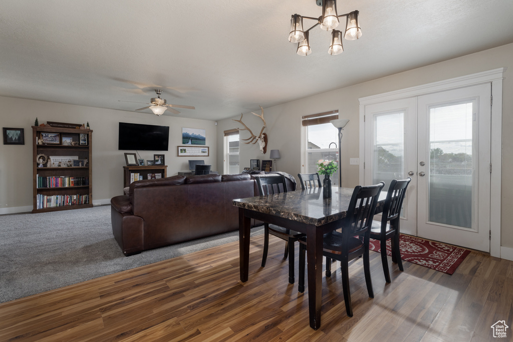 Dining area featuring ceiling fan, a chandelier, wood finished floors, baseboards, and french doors