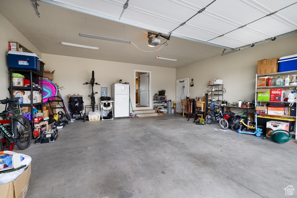 Garage featuring freestanding refrigerator and a garage door opener