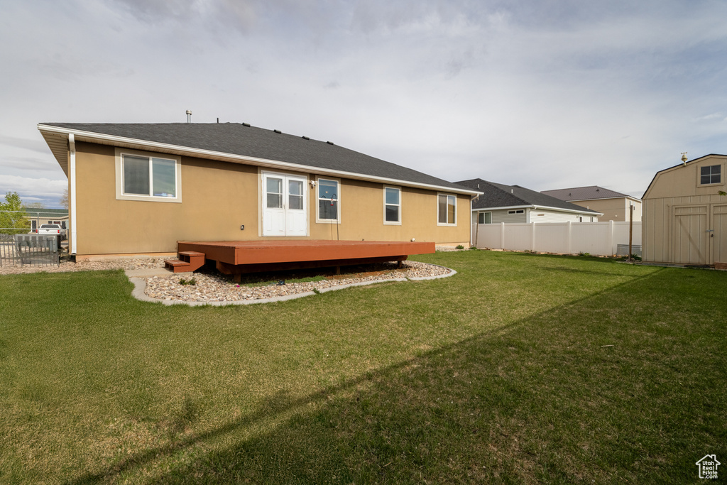 Back of house with a storage unit, an outdoor structure, and a deck