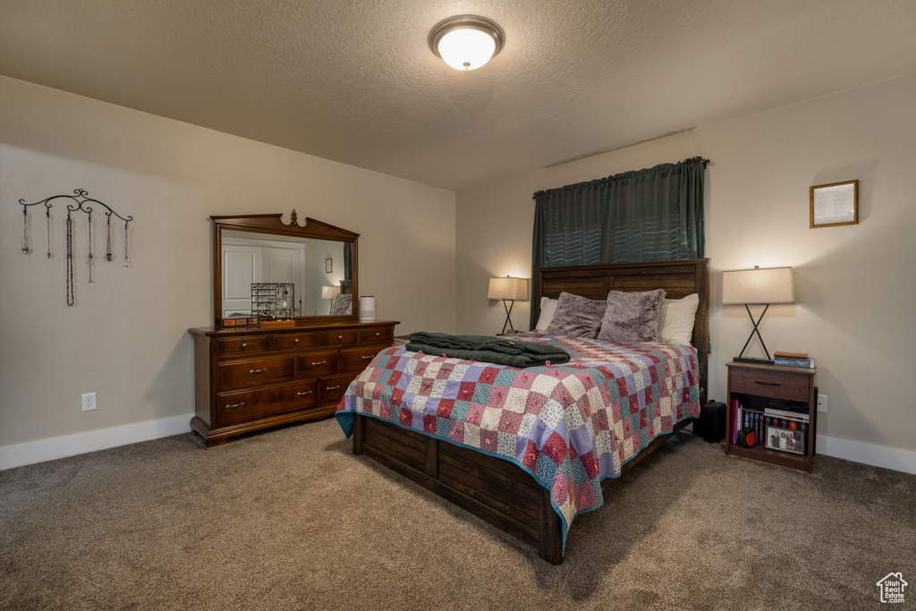 Carpeted bedroom featuring baseboards and a textured ceiling