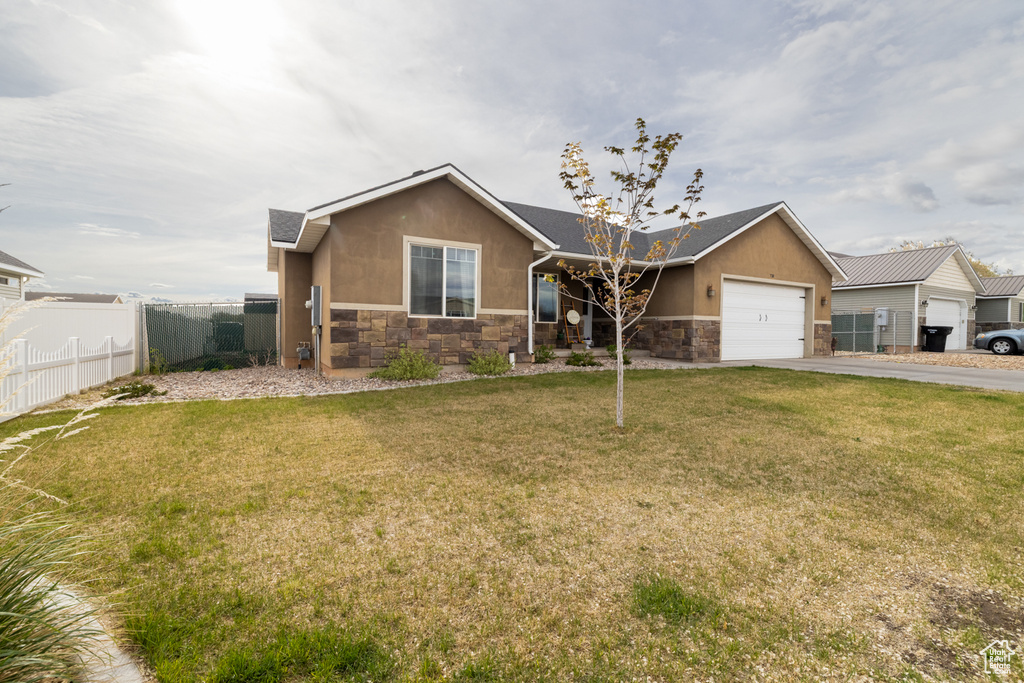 Ranch-style home with stone siding, concrete driveway, an attached garage, and stucco siding