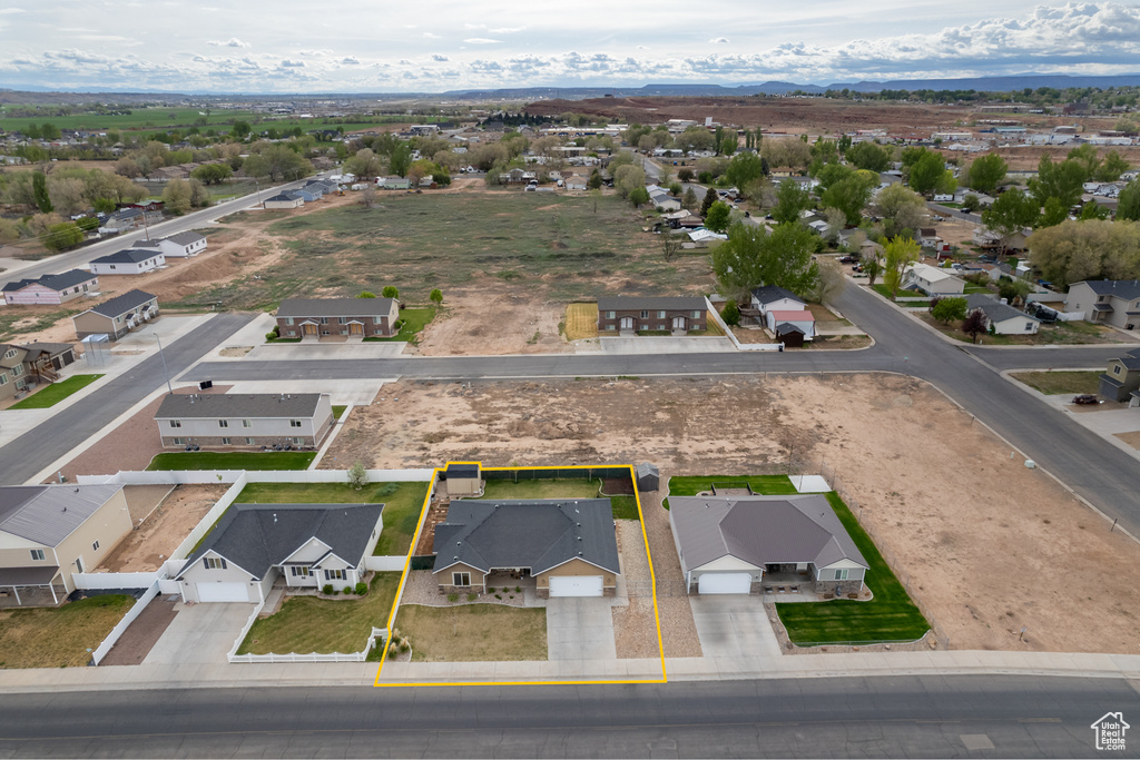 Aerial view of residential area with property parcel outlined and a mountainous background