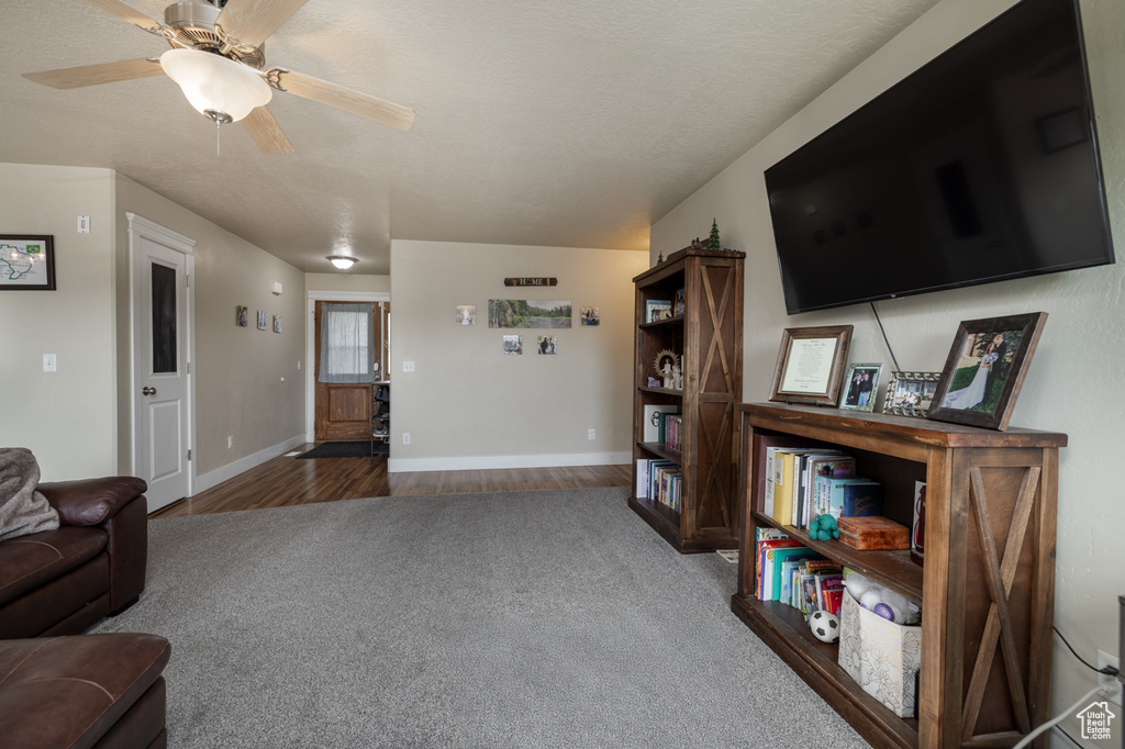 Carpeted living room featuring baseboards, wood finished floors, and a ceiling fan