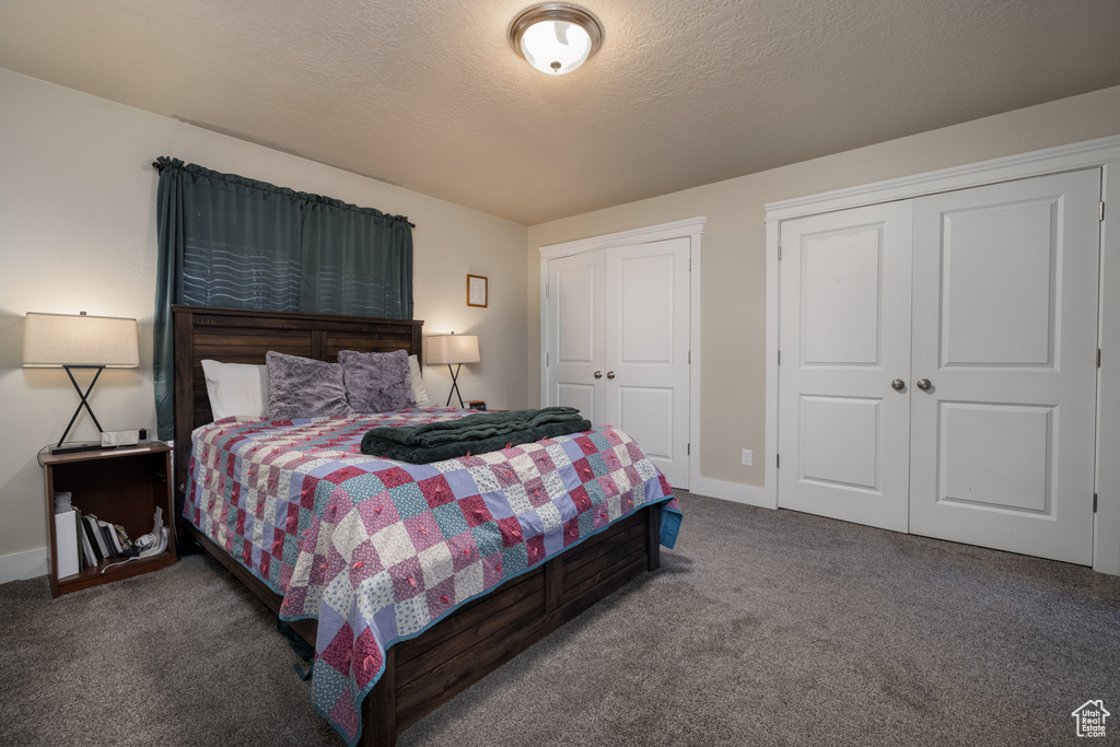 Bedroom with multiple closets, carpet, baseboards, and a textured ceiling