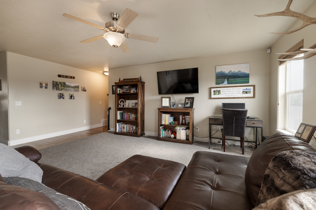 Carpeted living room with a ceiling fan and baseboards